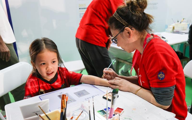 马会义工队在场外的马会互动摊位举办活动，为市民画上彩绘。