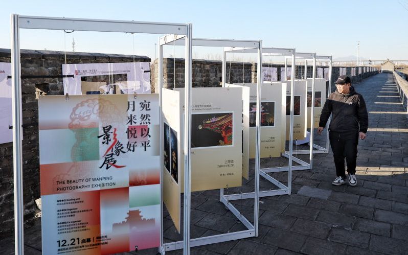 12月21日，丰台区系列跨年活动之“宛然以平 月来悦好”影像展开幕，市民游客在宛平城墙上参观摄影作品。新京报记者 陶冉 摄
