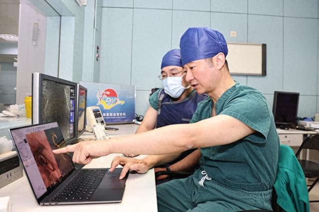 陆清声（右）在手术室外查看医学影像。长海医院 供图