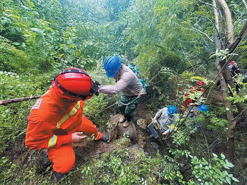 2025年7月27日，国网北京密云供电公司抢修人员携带应急发电设备，徒步进入冯家峪信号中断区域运送设备。林一轩 摄