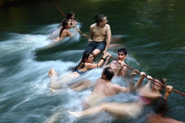 当地时间2025年7月1日，德国慕尼黑，人们在英国公园的艾斯巴赫河中抓着绳索，玩水纳凉。德国气象局警告称，该国大部分地区将出现热浪，气温最高可达38摄氏度。视觉中国 图