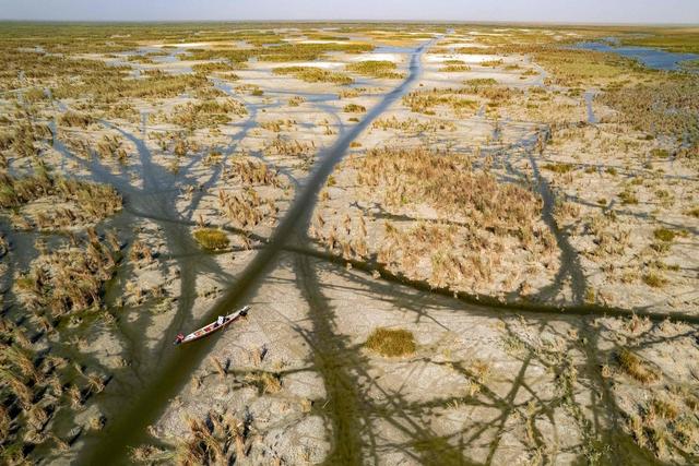 当地时间2025年7月30日，伊拉克南部济加尔省，一幅航拍画面捕捉到当地居民在奇巴伊什沼泽地的船只上休憩。这片沼泽因干旱水位消退，形成了纵横的沟渠。目前，伊拉克正面临着气温攀升、长期水资源短缺和连年干旱。视觉中国 图