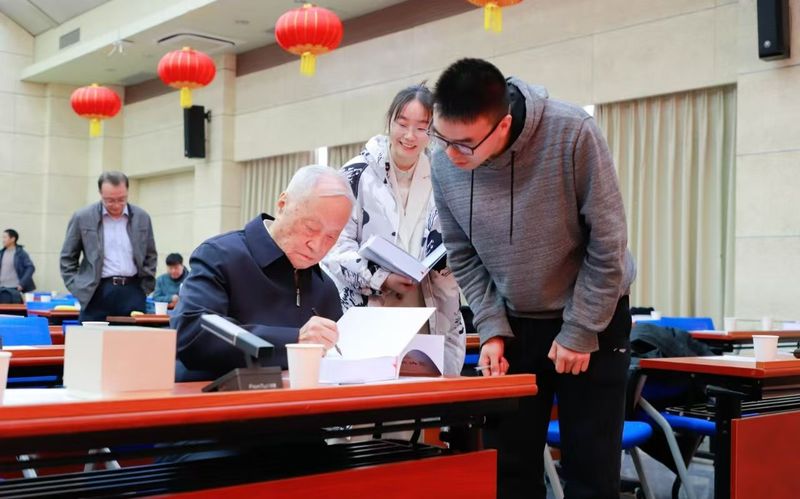 滕吉文（左）为青年学子签名赠书。首都文明办供图