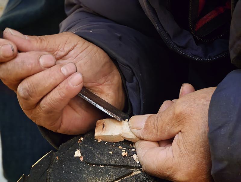 “木雕大爷”出摊后，一边回答网友问题一边雕刻。新京报记者 王巍 摄