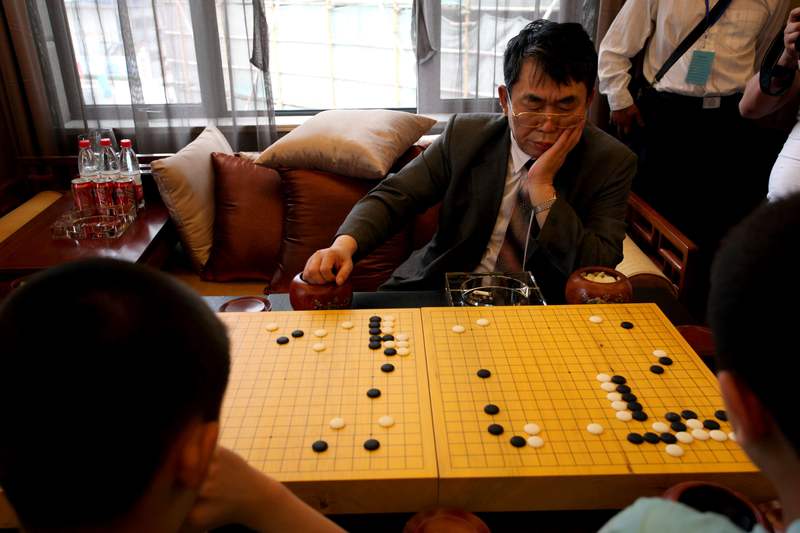 2012年6月16日，聂卫平在江苏淮安第二届“聂教室”小棋王赛上与优胜小选手下棋。资料图/IC photo