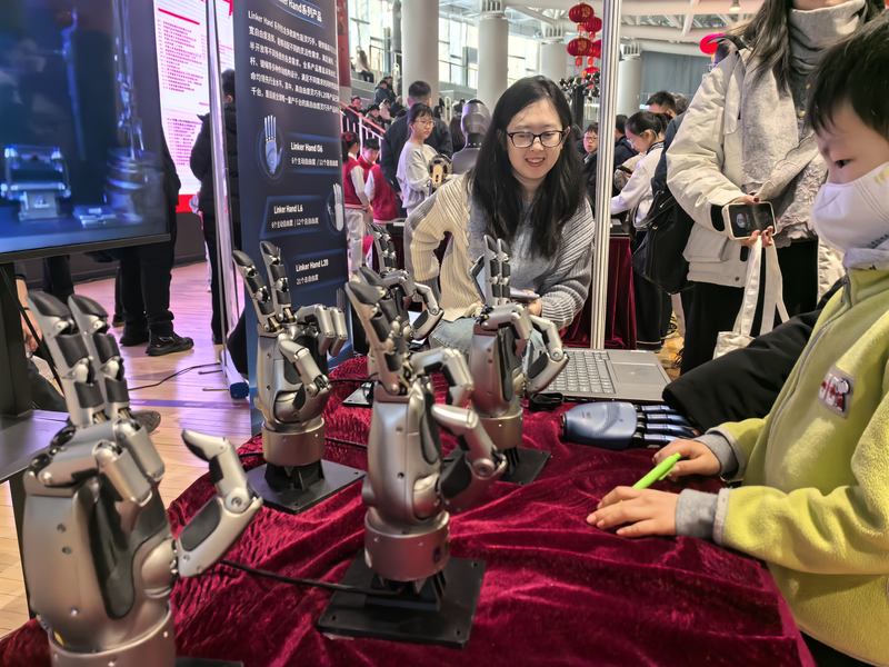 小学生与具身智能灵巧手玩“石头剪刀布”游戏。新京报记者 杨菲菲 摄