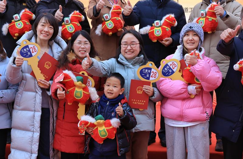 居民拿着新家的钥匙和房产证合影。新京报记者 薛珺 摄