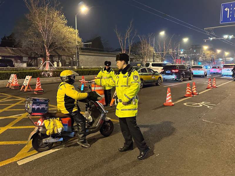 平安里附近一处夜查点位，执勤交警对一位骑行电动车的外卖小哥进行酒测。新京报记者 裴剑飞 摄