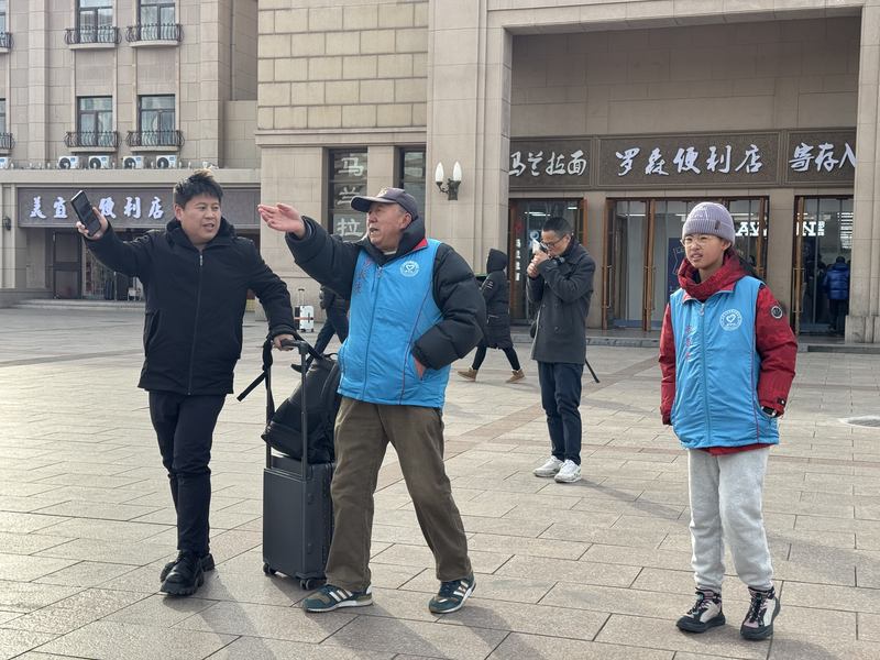 北京站站前广场，“北京站党员义务指路队”在为旅客指路。新京报记者 耿子叶 摄