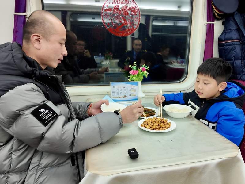 2月3日，来自福建的郑先生与孩子在1462次列车餐车体验现炒晚餐。新京报贝壳财经记者俞金旻 摄