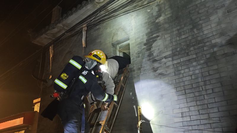 消防员用拉梯把被困者从窗户救出。丰台消防供图