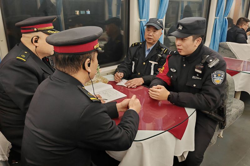 丁伟伦（最右）在列车上和乘务员探讨工作。北京铁警供图