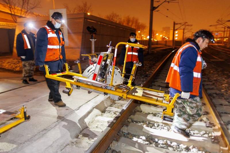 工人们将200多斤的打磨机搬运上轨道。