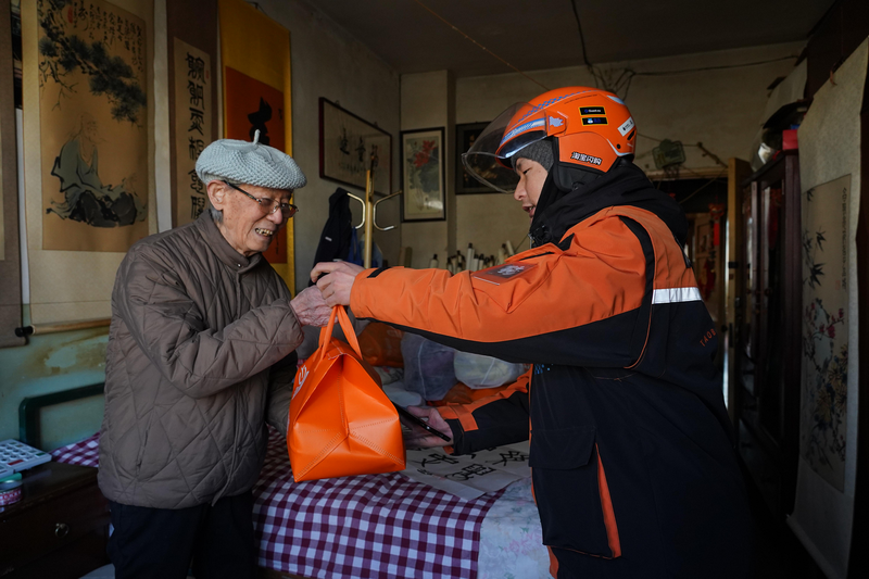 淘宝闪购城市骑士为社区老人送餐。