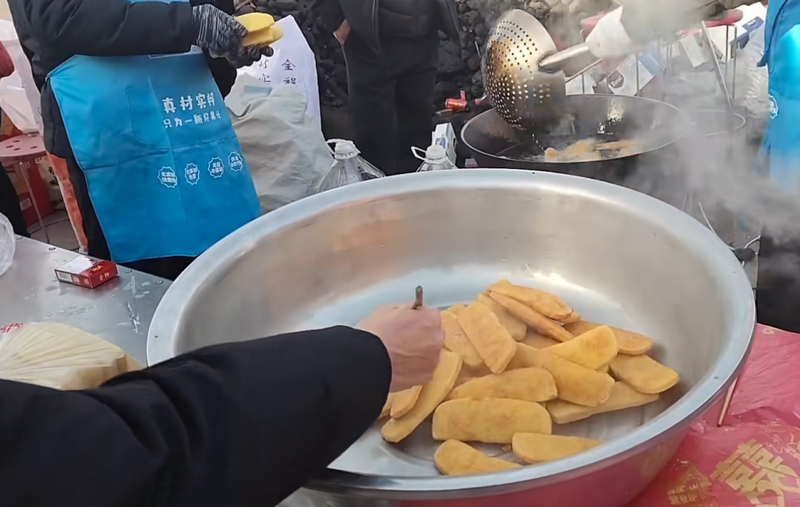 陕北农村红事乡宴上的炸油糕，这边出锅儿捞出来，那边就趁热吃上了。