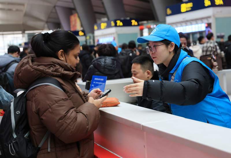 北京南站12306服务台，志愿者为外籍旅客提供出行指引。新京报记者 王远征 摄