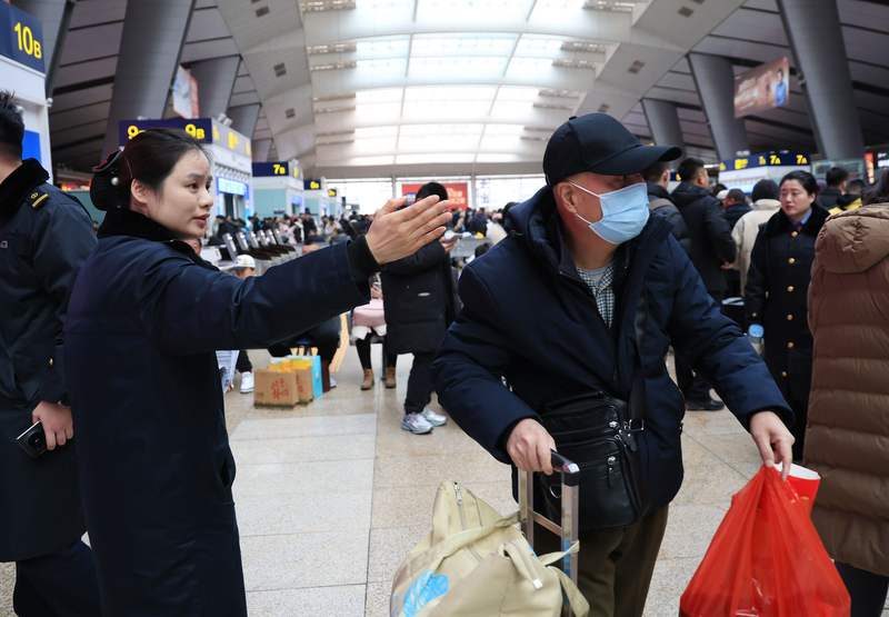 今天上午，北京南站继续迎来大客流，李玲为旅客指引检票口方向。新京报记者 王远征 摄