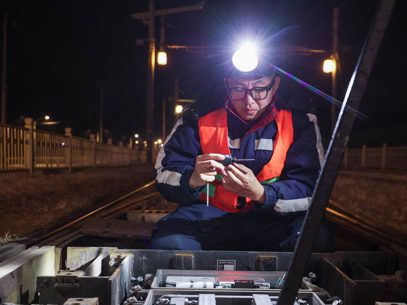 北京有轨电车西郊线通号维修班组维修工白子鹏蹲在地上检修设备。董万鑫 摄