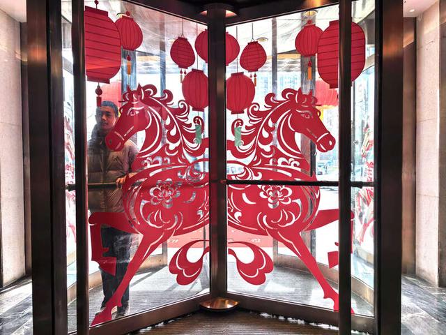 2月15日，北京东四环某饭店，转门玻璃上贴着生肖马年的剪纸图案。中青报·中青网记者 陈剑/摄