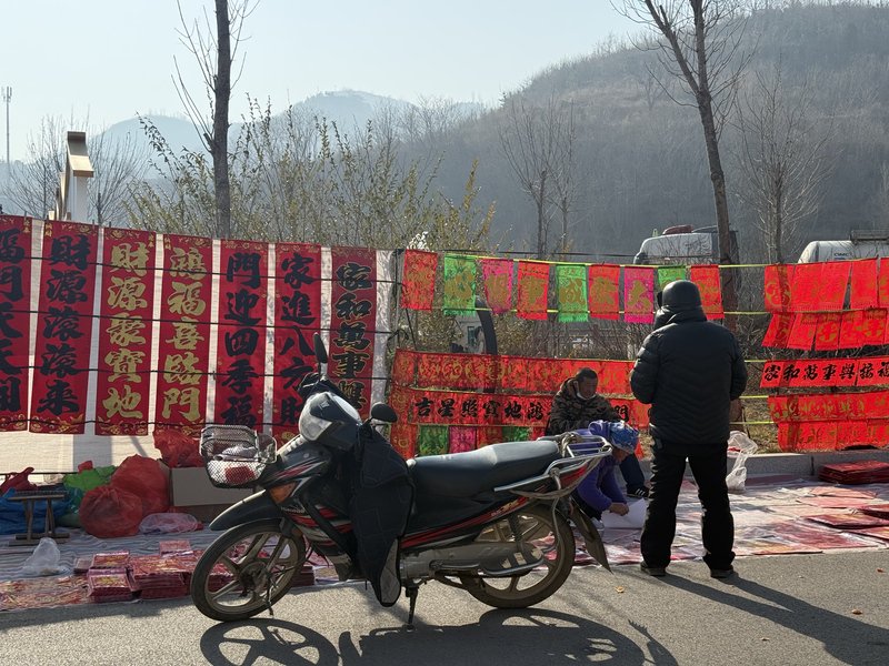 2月14日，农历腊月二十七，离我家最近的大集上的对联、年画，一位中年男子正在和摊主交谈。 新京报记者 赵敏 摄
