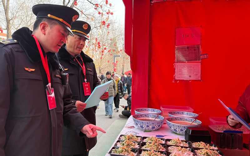 2月21日，龙潭庙会，崔杰（左一）和同事要求摊主对出售的食品进行遮盖，以保障干净卫生。新京报记者 陈琳 摄