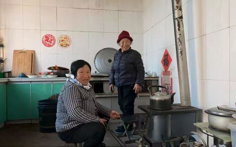 2月14日，腊月二十七，郁章宝的母亲（右）和小姨在厨房烧水、煮水饺。新京报记者 王巍 摄