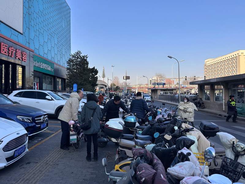 由于非机动车无序停放，堵住了正常停放机动车的通行道路，市民自行挪车清出道路。新京报记者 王贵彬 摄