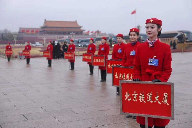 3月4日，天安门广场，两会服务保障人员手持引导牌等待会议结束。