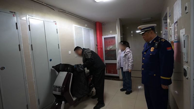 消防监督员劝导车主将停在楼道内的电动自行车推离。朝阳消防供图