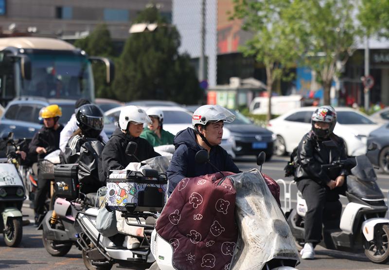 从今早的路面情况来看，约八成左右的电动车骑行者都能自觉佩戴好安全头盔。新京报记者 王贵彬 摄