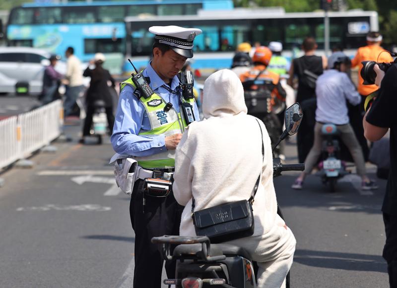 在崇文门路口交警对一位未佩戴安全头盔的电动自行车骑行者进行教育纠正。新京报记者 王贵彬 摄