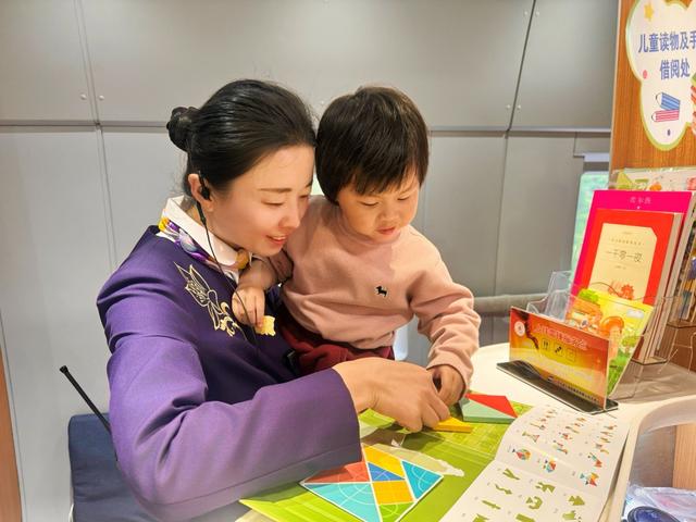 G7472次乘务员引导儿童旅客使用“童心旅伴”趣味角益智玩具。王昊 摄