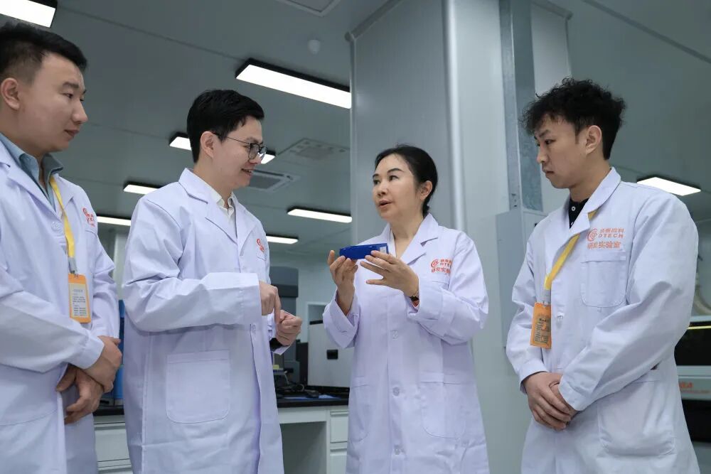 在广东鼎泰高科技术股份有限公司总部实验室，王馨（右二）与研发人员交流。新华社记者 毛思倩 摄
