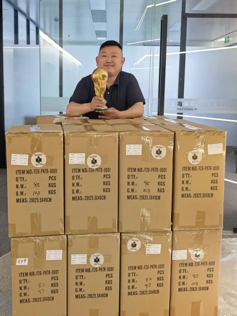 熊小锋与自家公司的大力神杯复制品合影。受访者供图