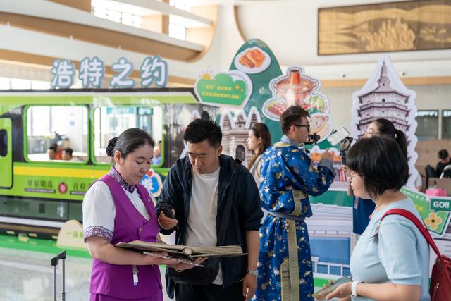 锡林浩特站工作人员向旅客介绍锡林浩特景点。 李小龙 摄
