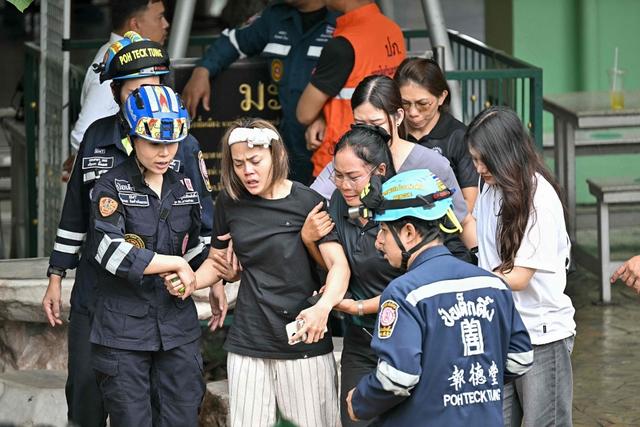 当地时间2026年8月7日，泰国暖武里府挽坤艾区，一名在校园枪击案中遇难教师的妻子（中）被送往救护车。视觉中国 图