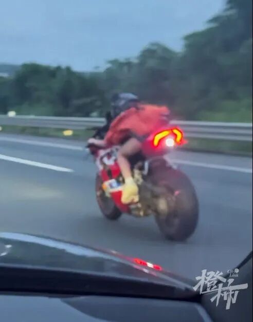 行驶途中，女骑手不断做出危险动作：单手握把骑行，另一只手操作手机，还频频回头，和后方保时捷车内人员互相拍摄