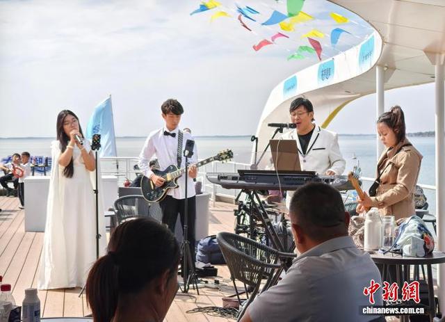 10月1日，山东东平，游客在“东平湖号”游船上观看乐队演出。 张欢 摄