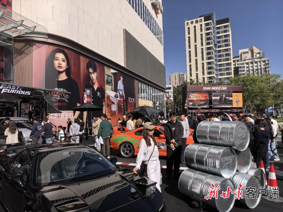 一顾客在兰州万象城门前广场与展示的汽车合影。
