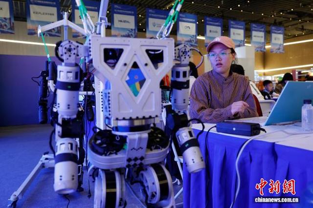图为在黑客松赛事项目区域，选手将编码植入机器人，并观察动作的执行情况。中新社记者 殷立勤 摄