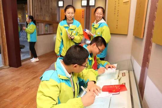 近年来掀起土楼研学热,图为学生们参观客家家训馆,寻找自己的姓氏家训,抄写客家祖训家规。