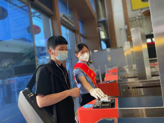 车站工作人员协助旅客刷身份证检票进站