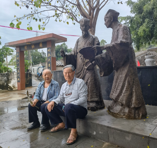 姜维民（右）、汪江涛在澄迈县老城镇国社村“东坡唐佐像”前。（姜深 摄）