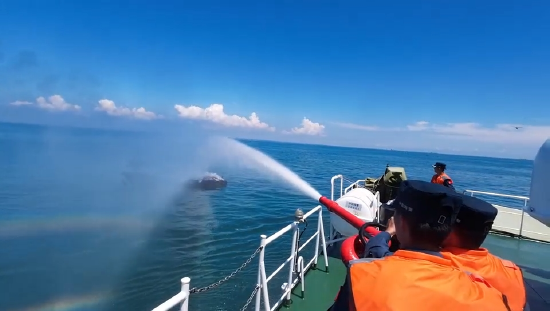 海警救援人员运用舰载水枪进行灭火