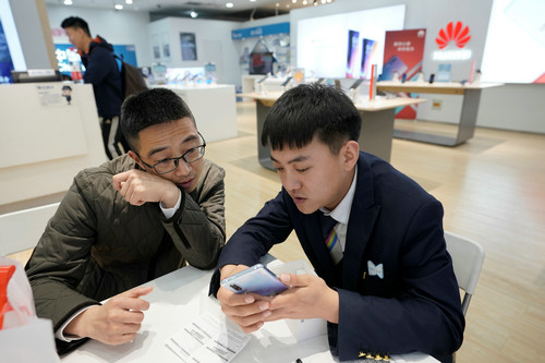 在北京的一家华为经销店内，一名销售人员正在向顾客展示华为手机。（路透社）