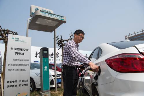  一名车主在重庆市内一处停车场为电动汽车充电。新华社