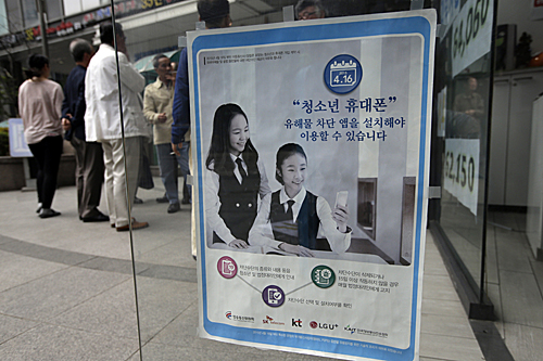  在韩国首都首尔一家手机商店，门口的玻璃门上贴着一张海报，介绍一种可以屏蔽有害网络信息的手机应用软件。（新华社）