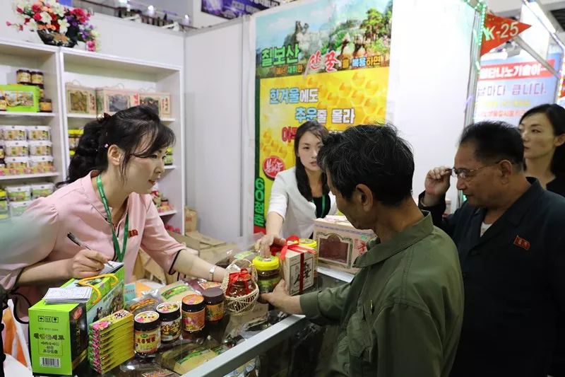 5月20日，在朝鲜平壤，朝鲜民众在一家销售蜂蜜的展台前选购蜂蜜产品。新华社记者程大雨摄