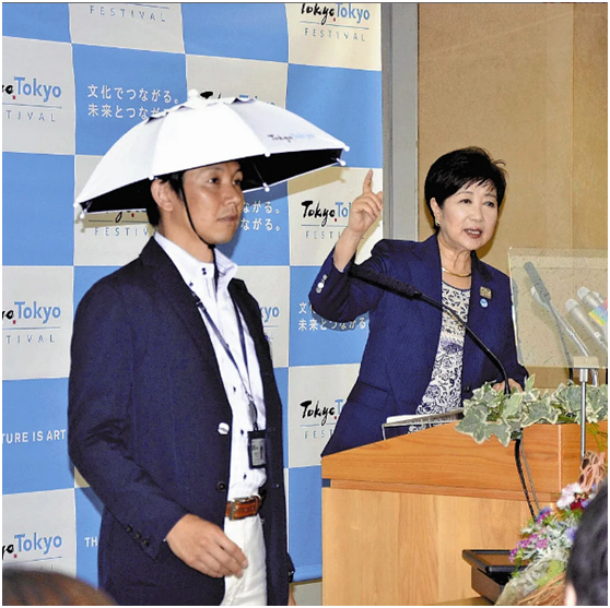 东京知事小池百合子在发布会上介绍“头戴式遮阳伞”。图源:《读卖新闻》
