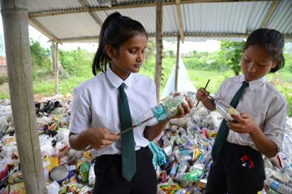 （学生们将塑料袋塞进塑料瓶里，制成“生态砖” 图源：法新社）